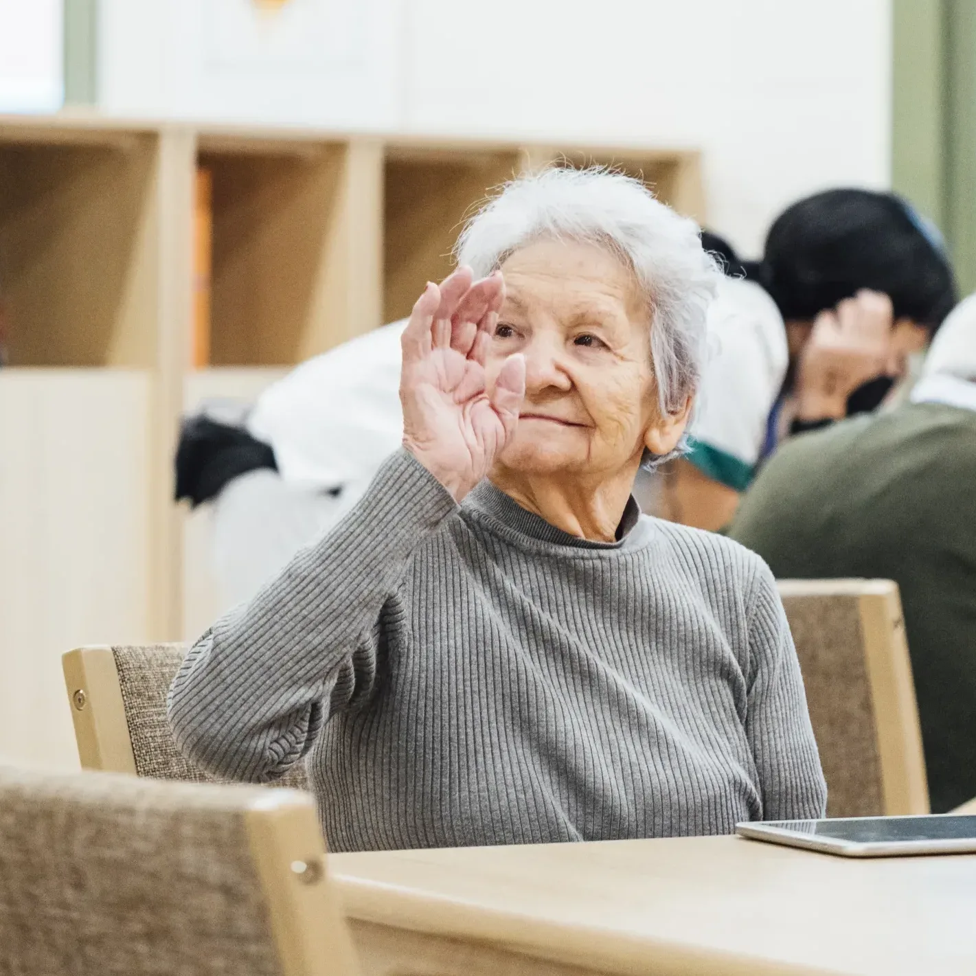 Señora mayor sonriendo y levantando la mano